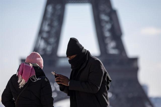 Una pareja que viste gorros y bufandas toma fotografías con su teléfono móvil en el Trocadero en París (Francia) EFE/ Ian Langsdon