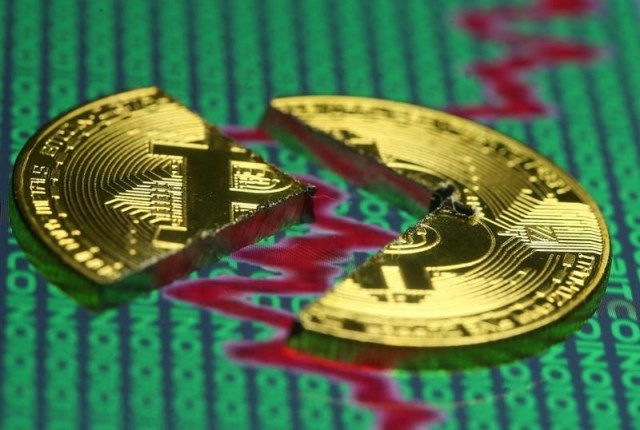 Ilustración fotográfica de una moneda de bitcoin rota sobre una pantalla con infromación financiera y código binario, dic 21, 2017. REUTERS/Dado Ruvic/Illustration