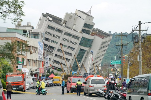 Trabajadores de rescate y emergencia bloquean una calle donde un edificio se desprendió de sus cimientos, la mañana después de que un terremoto de 6,4 grados de magnitud golpeara la ciudad taiwanesa oriental de Hualien, el 7 de febrero de 2018. / AFP PHOTO / PAUL YANG
