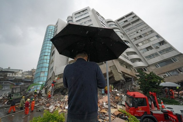 Un hombre reza frente a un edificio que se inclinó hacia un lado después de que su fundación colapsó en Hualien después de que un fuerte terremoto de magnitud 6,4 sacudió el este de Taiwan el 7 de febrero de 2018. / AFP PHOTO / PAUL YANG