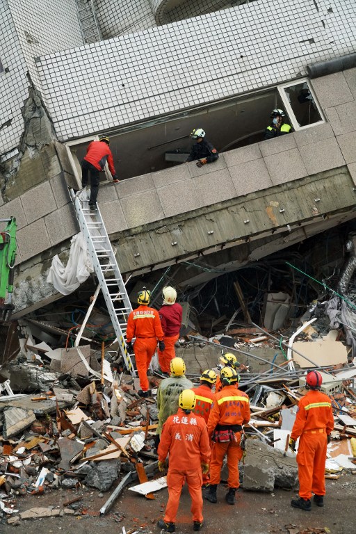 Los equipos de rescate registraron un edificio que se inclinó hacia un lado después de que su base colapsó en Hualien después de que un fuerte terremoto de magnitud 6,4 sacudió el este de Taiwan el 7 de febrero de 2018. / AFP PHOTO / PAUL YANG