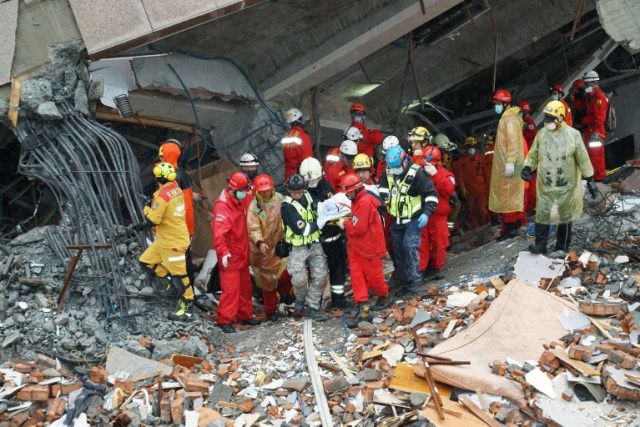 Los trabajadores de rescate llevan el cuerpo de una víctima desde un edificio que se inclinó hacia un lado después de que su fundación colapsó en Hualien después de que un fuerte terremoto de magnitud 6,4 sacudió el este de Taiwan el 7 de febrero de 2018. / AFP PHOTO / Paul YANG