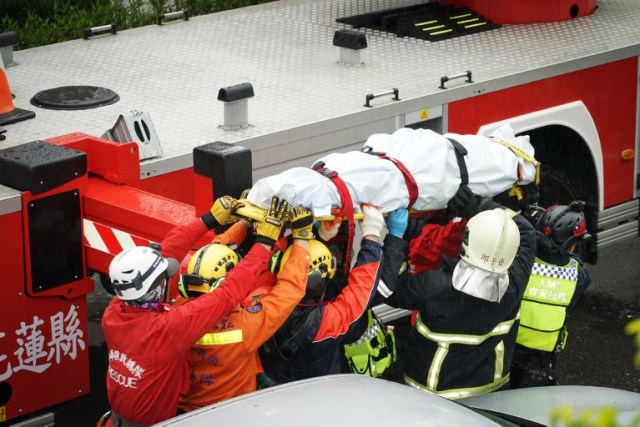 Los equipos de rescate llevan el cuerpo de una víctima desde un edificio que se inclinó hacia un lado después de que su fundación colapsó en Hualien después de que un fuerte terremoto de magnitud 6,4 sacudió el este de Taiwan el 7 de febrero de 2018. / AFP PHOTO / PAUL YANG