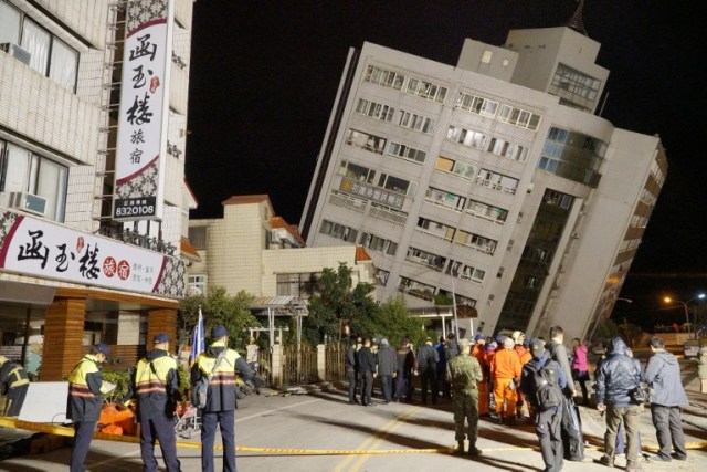 Rescue workers block off the area to search for survivors outside a building which tilted to one side after its foundation collapsed in Hualien after a strong 6.4-magnitude quake rocked eastern Taiwan early on February 7, 2018. / AFP PHOTO / Paul YANG