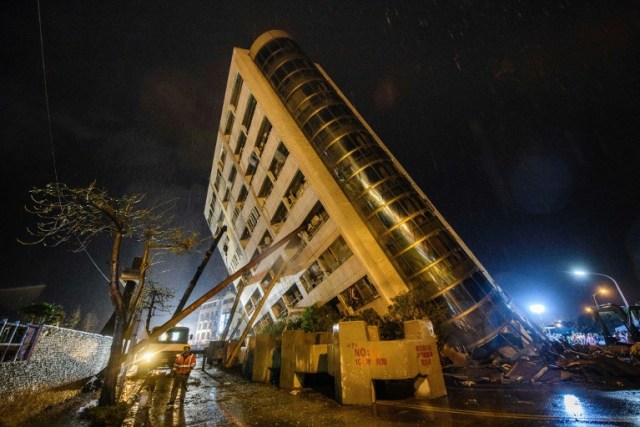 Un trabajador de rescate (parte inferior L) pasa junto a las vigas utilizadas para apuntalar el edificio Yun Tsui cuando se inclina hacia un lado después de un terremoto en la ciudad taiwanesa de Hualien el 7 de febrero de 2018. / AFP PHOTO / Anthony WALLACE