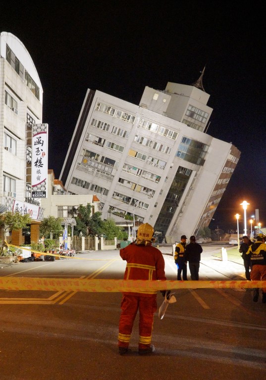 Los equipos de rescate bloquean el área exterior de un edificio que se inclinó hacia un lado después de que su fundación colapsó en Hualien después de que un fuerte terremoto de magnitud 6,4 sacudió el este de Taiwan el 7 de febrero de 2018. / AFP PHOTO / Paul YANG