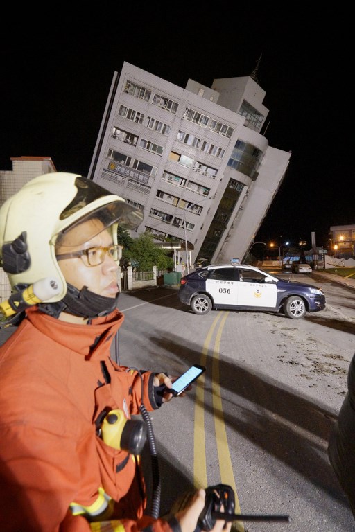 Los equipos de rescate bloquean el área exterior de un edificio que se inclinó hacia un lado después de que su fundación colapsó en Hualien después de que un fuerte terremoto de magnitud 6,4 sacudió el este de Taiwan el 7 de febrero de 2018. / AFP PHOTO / Paul YANG