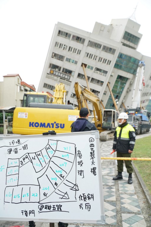 Trabajadores de rescate y emergencia bloquean una calle donde un edificio se desprendió de sus cimientos, la mañana después de que un terremoto de 6,4 grados de magnitud golpeara la ciudad taiwanesa oriental de Hualien, el 7 de febrero de 2018. / AFP PHOTO / PAUL YANG