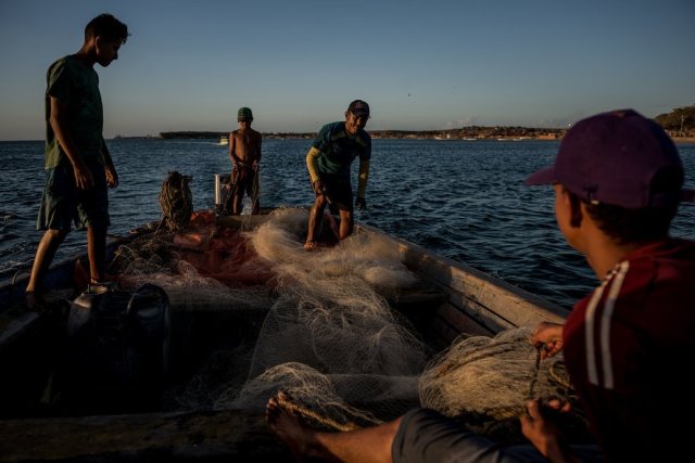 Pescando en la bahía de Amuay. La refinería más grande de Venezuela ha vertido contaminantes al agua, lo que pone en riesgo el sustento de las familias en el área. Credit Meridith Kohut para The New York Times
