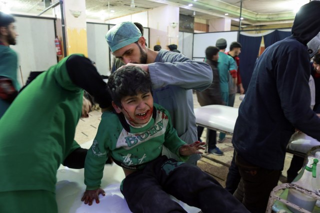 EDITORS NOTE: Graphic content / Paramedics tend to the injuries of a Syrian child who was wounded during reported regime bombardment, at a make-shift clinic in the rebel-held town of Douma, in the besieged Eastern Ghouta region on the outskirts of the capital Damascus on February 24, 2018. / AFP PHOTO / HAMZA AL-AJWEH