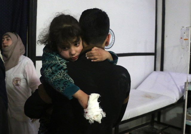 A lightly wounded Syrian girl is carried by a man at a makeshift clinic following Syrian government bombardments in Douma, in the besieged Eastern Ghouta region on the outskirts of the capital Damascus on February 22, 2018.  Fresh bombardment on Eastern Ghouta killed dozens today, bringing the number of dead civilians in a five-day assault by the Syrian government to more than 400. / AFP PHOTO / Hamza AL-AJWEH