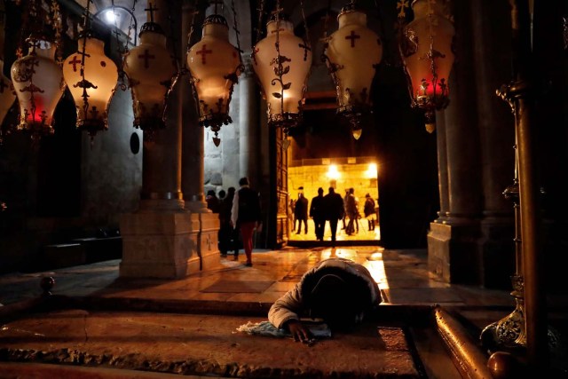 A Christian worshipper prays on the anointing stone inside the Church of the Holy Sepulchre after it reopened on February 28, 2018 following a three-day closure to protest against Israeli tax measures and a proposed law. Jerusalem's Church of the Holy Sepulchre, seen by many as the holiest site in Christianity, reopened on February 28 after a three-day closure to protest against Israeli tax measures and a proposed law. / AFP PHOTO / Thomas COEX