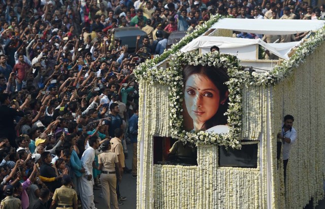 Indian fans watch as the funeral cortege of the late Bollywood actress Sridevi Kapoor passes through Mumbai on February 28, 2018. Thousands of heartbroken fans lined the streets of Mumbai February 28 as India said farewell to Bollywood legend Sridevi Kapoor following her shock death from accidental drowning in a Dubai hotel bathtub aged just 54. / AFP PHOTO / PUNIT PARANJPE