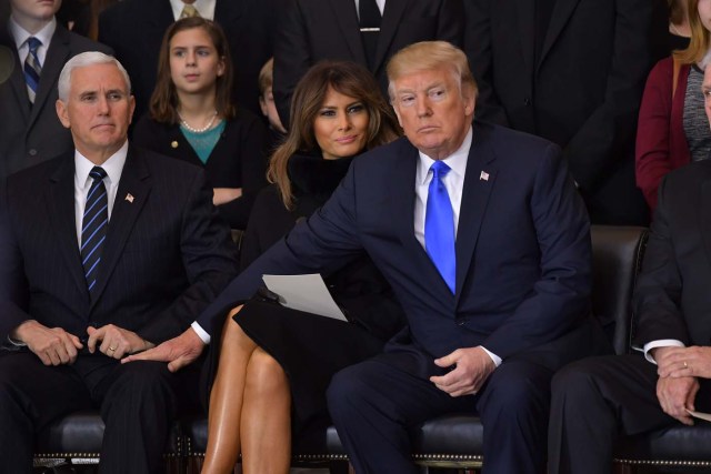 President Donald Trump (R)reaches for Vice President Mike Pence as US First Lady Melania Trump looks on, during the memorial service for Reverend Billy Graham in the Rotunda of the US Capitol on February 28, 2018 in Washington, DC. / AFP PHOTO / Mandel NGAN