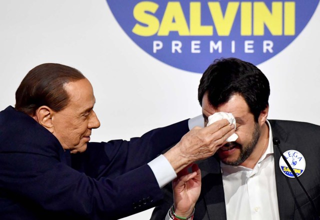 Leader of the centre-right Forza Italia (Go Italy) Silvio Berlusconi (L) wipes the forehead of leader of far-right party the League Matteo Salvini, as he jokes with him during a joint press conference with leader of far-right party Brothers of Italy (unseen) at the Tempio di Adriano in Rome on March 1, 2018. Silvio Berlusconi's rightwing coalition, which is on course to win the most votes in Italy's election, is holding its first and last public meeting on March 1 in an attempt to quell speculation of severe internal divisions. Berlusconi, the flamboyant 81-year-old former prime minister and head of the centre-right Forza Italia (Go Italy), and the leaders of far-right parties the League and Brothers of Italy (FdI), Matteo Salvini and Giorgia Meloni, have not once met publicly in the entire election campaign. / AFP PHOTO / Alberto PIZZOLI