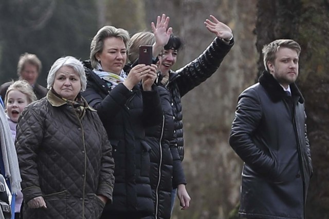 People wave-off others that left the Russian Embassy in London on March 20, 2018 carrying luggage and boarded a van bearing diplomatic plates. Dozens of people including adults with children arrived at the Russian embassy on March 20 morning and then left carrying luggage in vehicles bearing diplomactic registration plates. Britain last week announced the expulsion of 23 Russian diplomats over the spy poisoning row, prompting a tit-for-tat response from Moscow. / AFP PHOTO / Daniel LEAL-OLIVAS