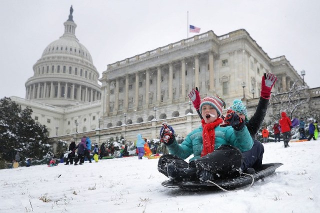 WASHINGTON, DC - MARCH 21: People snow sled on the grounds of the U.S. Capitol March 21, 2018 in Washington, DC. An early spring storm brought several inches of snow to the East Coast, the fourth nor'easter in recent weeks.   Chip Somodevilla/Getty Images/AFP