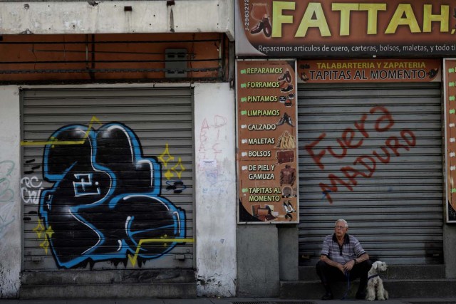 A man with a dog sits in front of a closed shop during a strike called to protest against Venezuelan President Nicolas Maduro's government in Caracas, Venezuela July 26, 2017. REUTERS/Ueslei Marcelino
