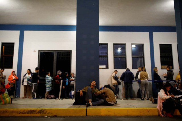 Adrian Naveda (C) and Natacha Rodriguez, who are traveling by bus from Caracas to Chile, sleep sitting on the floor while they wait in line to have their passport stamped at the binational border service centre in Huaquillas, Ecuador, November 11, 2017. After four days of traveling, the fatigue among the passengers was evident. Having boarded the last bus in Guayaquil after midnight and travelled approximately four hours to the border between Ecuador and Peru, many fell asleep on the floor while queuing to get their passports stamped. REUTERS/Carlos Garcia Rawlins SEARCH "RAWLINS BUS" FOR THIS STORY. SEARCH "WIDER IMAGE" FOR ALL STORIES.