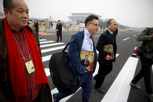 Delegates holding magazines featuring Chinese President Xi Jinping on the cover arrive for the opening session of the Chinese People's Political Consultative Conference (CPPCC) at the Great Hall of the People in Beijing, China March 3, 2018. REUTERS/Thomas Peter