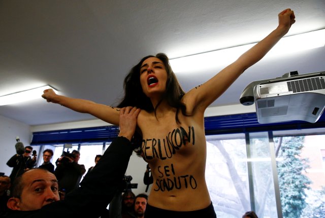 Una activista en topless del grupo Femen de derechos femeninos interrumpe la votación cuando el líder del partido Forza Italia, Silvio Berlusconi (no en la foto) lanza su voto en un colegio en Milán, Italia el 4 de marzo de 2018. El mensaje dice: "Berlusconi, te has terminado". REUTERS / Stefano Rellandini 