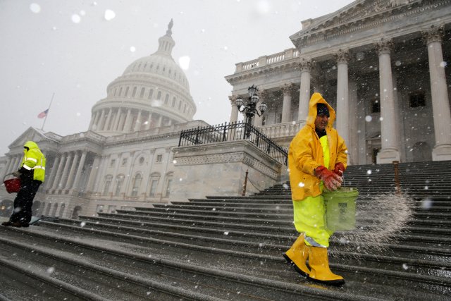 Workers spread salt on the steps of the U.S. Capitol as light snow falls in Washington, U.S. March 21, 2018. REUTERS/Jonathan Ernst
