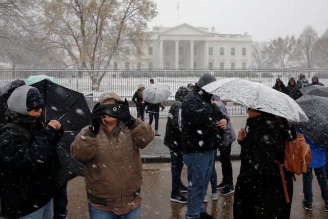 Tourists gather and take pictures as light snow falls in front of the White House in Washington, U.S. March 21, 2018. REUTERS/Jonathan Ernst