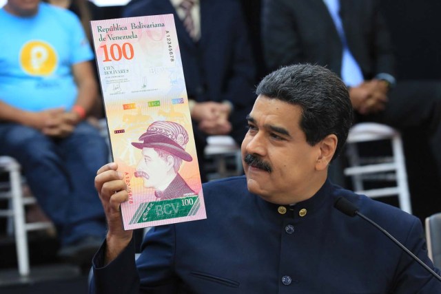 Venezuela's President Nicolas Maduro holds a sample of the new hundred bolivars note during a meeting with the ministers responsible for the economic sector at Miraflores Palace in Caracas, Venezuela March 22, 2018. Miraflores Palace/Handout via REUTERS ATTENTION EDITORS - THIS PICTURE WAS PROVIDED BY A THIRD PARTY.