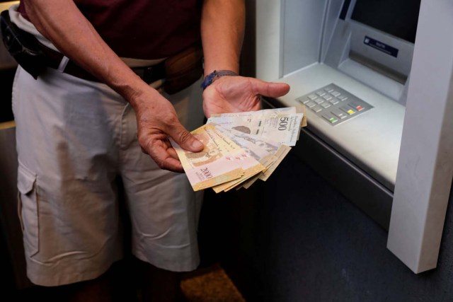 A man shows Bolivar notes after withdrawing them from an automated teller machine (ATM) in Caracas, Venezuela March 23, 2018. REUTERS/Marco Bello