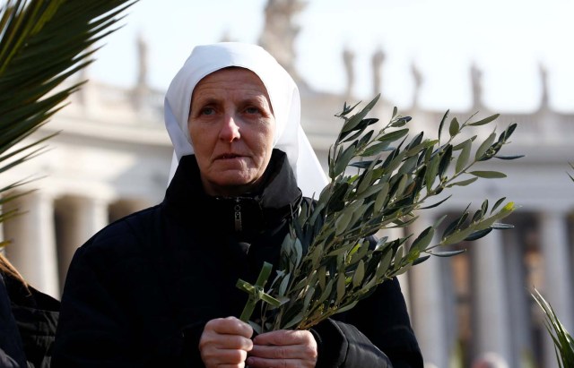 A nun holds palms and crosses made of palm leaves during the Palm Sunday Mass in Saint Peter's Square at the Vatican, March 25, 2018 REUTERS/Stefano Rellandini