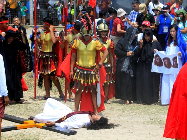 Ruben Enaje, 58, who is portraying Jesus Christ for the 32nd time, lies on the ground as residents in the role of Centurions looks on during a Good Friday crucifixion re-enactment in Cutud village, Pampanga province, north of Manila, Philippines March 30, 2018. REUTERS/Romeo Ranoco