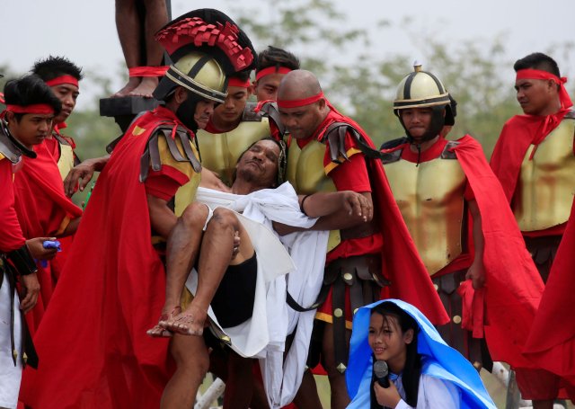 Ruben Enaje, 58, who is portraying Jesus Christ for the 32nd time, is carried by residents dressed as Centurions after he was nailed on a wooden cross during a Good Friday crucifixion re-enactment in Cutud village, Pampanga province, north of Manila, Philippines March 30, 2018. REUTERS/Romeo Ranoco
