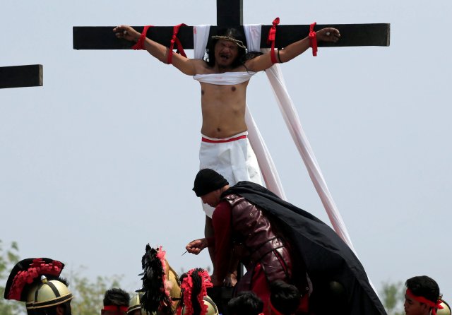 Ruben Enaje, 58, who is portraying Jesus Christ for the 32nd time, grimaces in pain as a resident in the role of a Centurion removes a nail from his feet during a Good Friday crucifixion re-enactment in Cutud village, Pampanga province, north of Manila, Philippines March 30, 2018. REUTERS/Romeo Ranoco