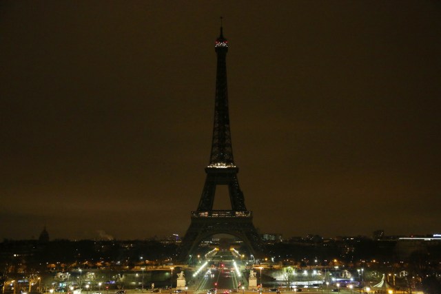 The lights of the Eiffel Tower are dimmed at midnight, March 23, 2018 in Paris to honor victims killed at a supermarket in southwest France by a man claiming allegiance to the Islamic State. Paris Mayor Anne Hidalgo announced that the Eiffel Tower would switch off its light at midnight to honour the victims. / AFP PHOTO / Zakaria ABDELKAFI