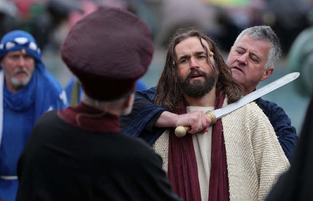 Actor James Burke-Dunsmore (2R) plays the role of Jesus Christ, during a performance of Wintershall's 'The Passion of Jesus' on Good Friday in Trafalgar Square in London on March 30, 2018.  The Passion of Jesus tells the story from the Bible of Jesus's visit to Jerusalem and his crucifixion. On Good Friday 20,000 people gather to watch the Easter story in central London. One hundred Wintershall players bring their portrayal of the final days of Jesus to this iconic location in the capital. / AFP PHOTO / Daniel LEAL-OLIVAS