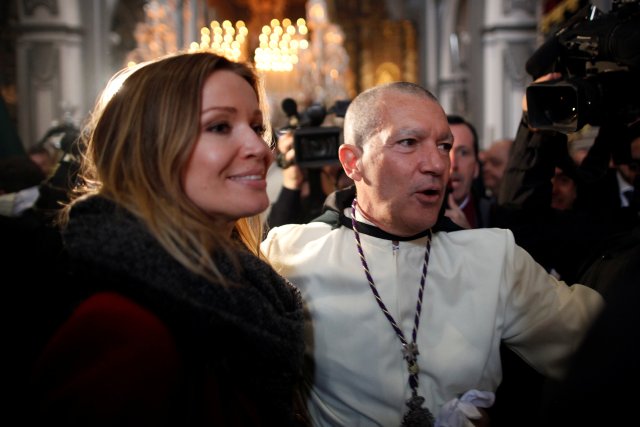 Spanish actor Antonio Banderas and his girlfriend Nicole Kimpel smile inside a church before taking part as a penitent in the "Lagrimas and Favores" brotherhood, during a Palm Sunday procession in Malaga, Spain March 25, 2018. REUTERS/Jon Nazca