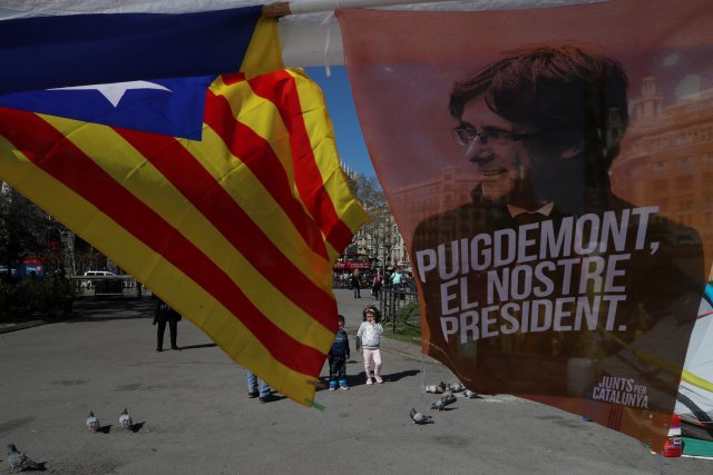 A banner, in support of former Catalan President Carles Puigdemont, is seen next to a Catalan separatist "Estelada" flag, at a camp-out protest calling for the Catalan Republic and against the imprisonment of Catalan separatist leaders in Barcelona, Spain March 28, 2018. The banner reads: "Puigdemont, our president". REUTERS/Susana Vera