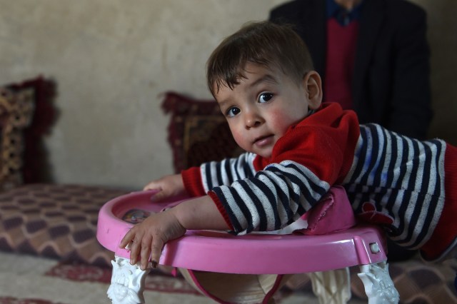 This picture taken on March 16, 2018 shows Afghan toddler Donald Trump, who is aged around 18 months, playing at his home in Kabul. Donald Trump flops over his pink and white baby walker and rolls it around the unfurnished room in Kabul, blissfully unaware of the turmoil his "infidel" name is causing in the conservative Muslim country. The rosy-cheeked toddler, whose parents named him after the more famous Donald Trump in the hope of replicating his success, is at the centre of a social media firestorm after a photo of his Afghan ID papers was posted on Facebook. / AFP PHOTO / Wakil KOHSAR / TO GO WITH 'AFGHANISTAN-PEOPLE-RELIGION' BY ALLISON JACKSON AND MUSHTAQ MOJADDIDI
