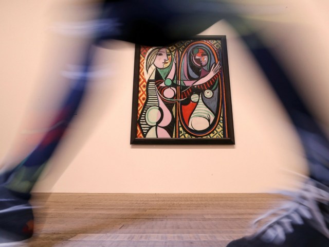Una empleada pasa caminando mientras posa con la pintura de Picasso "Girl before a Mirror" en la exposición Picasso 1932 - Love, Fame, Tragedy en la Tate Modern de Londres. /Foto Reuters 