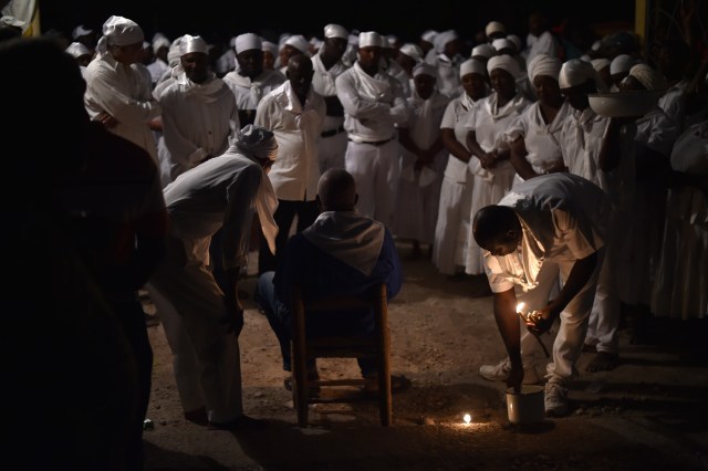 Haitian voodoo followers wearing white clothes participate in a voodoo ceremony in Souvenance, a suburb of Gonaives, 171km north of Port-au-Prince, on March 31, 2018. Haitian voodoo followers arrived in Souvenance to take part in the voodoo ceremonies held during Easter weekend. / AFP PHOTO / Hector RETAMAL