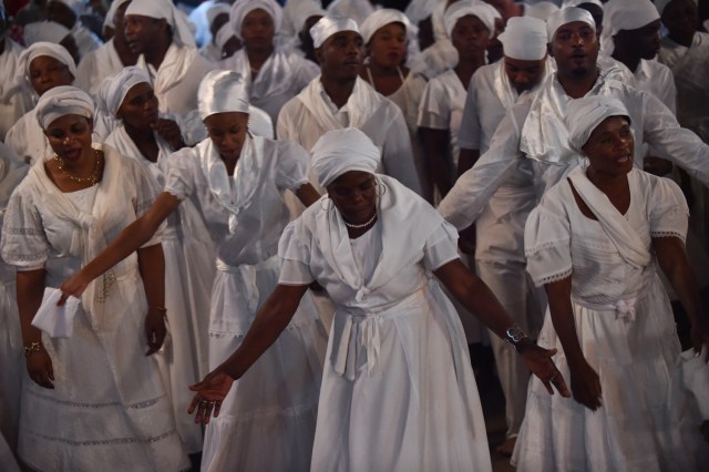 Haitian voodoo followers wearing white clothes dance while participating in a voodoo ceremony in Souvenance, a suburb of Gonaives, 171km north of Port-au-Prince, on March 31, 2018. Haitian voodoo followers arrived in Souvenance to take part in the voodoo ceremonies held during Easter weekend. / AFP PHOTO / Hector RETAMAL