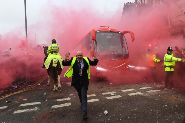 Police hold back supporters as Liverpool players arrive by bus at the stadium before the UEFA Champions League first leg quarter-final football match between Liverpool and Manchester City, at Anfield stadium in Liverpool, north west England on April 4, 2018. / AFP PHOTO / Paul ELLIS