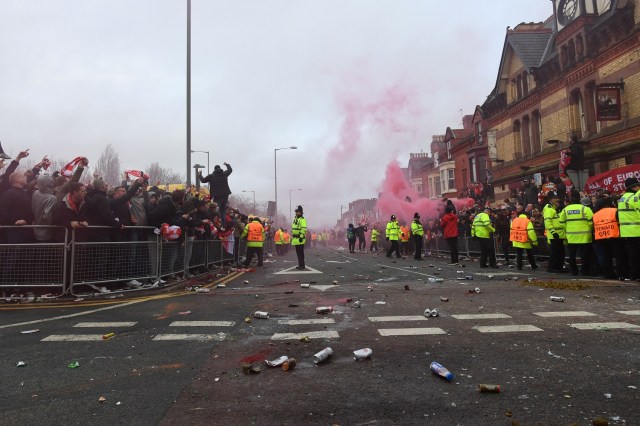 Police control supporters through smoke and beercans before the UEFA Champions League first leg quarter-final football match between Liverpool and Manchester City, at Anfield stadium in Liverpool, north west England on April 4, 2018. / AFP PHOTO / Paul ELLIS