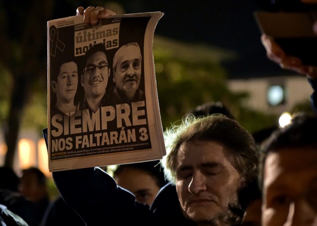 A man holds a newspaper during a tribute to Ecuadorean murdered journalist Javier Ortega, photographer Paul Rivas and their driver Efrain Segarra, in front of Metropolitan Cathedral, in Quito on April 13, 2018. The three members of an Ecuadoran journalist team who died in captivity after being abducted by a Colombian rebel group were following a story on violence that ended up costing their lives. / AFP PHOTO / RODRIGO BUENDIA