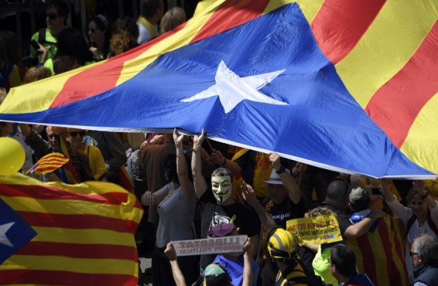 People carry a big Catalan pro-independence 'estelada' flag during a demonstration to support Catalan pro-independence jailed leaders and politicians and called by 'Espai Democracia i Convivencia' platform that groups separatist collectives and unions in Barcelona on April 15, 2018.  Thousands of people marched in Barcelona today to protest the jailing of nine Catalan separatist leaders facing trial on "rebellion" charges. Many chanted "Freedom for the political prisoners" as they massed on the Parallel Avenue, one of the city's main streets, wearing yellow scarves, sweaters or jackets -- the colour chosen to show solidarity with the jailed leaders.  / AFP PHOTO / LLUIS GENE