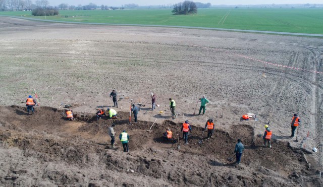 This aerial picture taken with a drone on April 13, 2018 shows archaeologists looking for a treasure in Schaprode, northern Germany. A 13-year-old boy and a hobby archaeologist have unearthed a "significant" trove in Germany which may have belonged to the legendary Danish king Harald Bluetooth who brought Christianity to Denmark. A dig covering 400 square metres (4,300 square feet) that finally started over the weekend by the regional archaeology service has since uncovered a trove believed linked to the Danish king who reigned from around 958 to 986. Braided necklaces, pearls, brooches, a Thor's hammer, rings and up to 600 chipped coins were found, including more than 100 that date back to Bluetooth's era. / AFP PHOTO / dpa / Stefan Sauer / Germany OUT