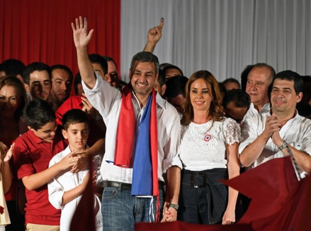 Paraguay's new President and presidential candidate of the Colorado Party, Mario Abdo Benitez (L), next to his wife Silvana Lopez Moreira, wave to the crowd at Partido Colorado headquarters in Asuncion on April 22, 2018 Mario Abdo Benitez, who represents Paraguay's long-dominant Colorado conservatives, won Sunday's presidential poll, landing the top job in one of Latin America's poorest countries, election officials said. / AFP PHOTO / EITAN ABRAMOVICH