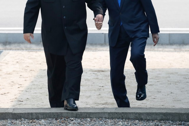 El líder norcoreano Kim Jong Un (izq.) Acompaña al presidente surcoreano Moon Jae-in (R) a través de la línea de demarcación militar que divide a sus países en el lado sur antes de su reunión en la cumbre oficial del edificio Peace House en Panmunjom el 27 de abril , 2018. Los dos hombres retrocedieron brevemente por la línea hacia el norte antes de caminar hacia el edificio de la Casa de la Paz en el lado sur de la aldea de tregua de Panmunjom para la cumbre, solo el tercero de este tipo desde que cesaron las hostilidades en 1953. / AFP PHOTO / Cumbre de prensa de Corea / Grupo de prensa de la cumbre de Corea