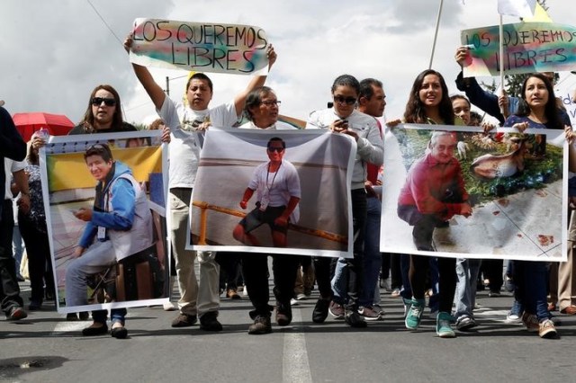 Familiares y amigos tienen fotos del periodista gráfico ecuatoriano Paul Rivas (izquierda), el periodista Javier Ortega (centro) y su conductor Efraín Segarra, quienes fueron secuestrados cerca de la frontera con Colombia, Quito, Ecuador 1 de abril , 2018. REUTERS / Daniel Tapia
