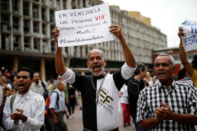 People take part in a protest due to the shortages of medicines outside the Health Ministry in Caracas, Venezuela April 18, 2018. The placard reads, "In Venezuela, we, HIV patients, have been sentenced to death". REUTERS/Carlos Garcia Rawlins
